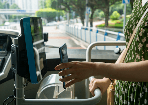 A person uses contactless payment on their smartphone to pay for their bus fare as they board. Image by QinJin via Shutterstock