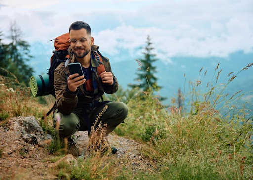 Young man on a smartphone while hiking in the mountains.