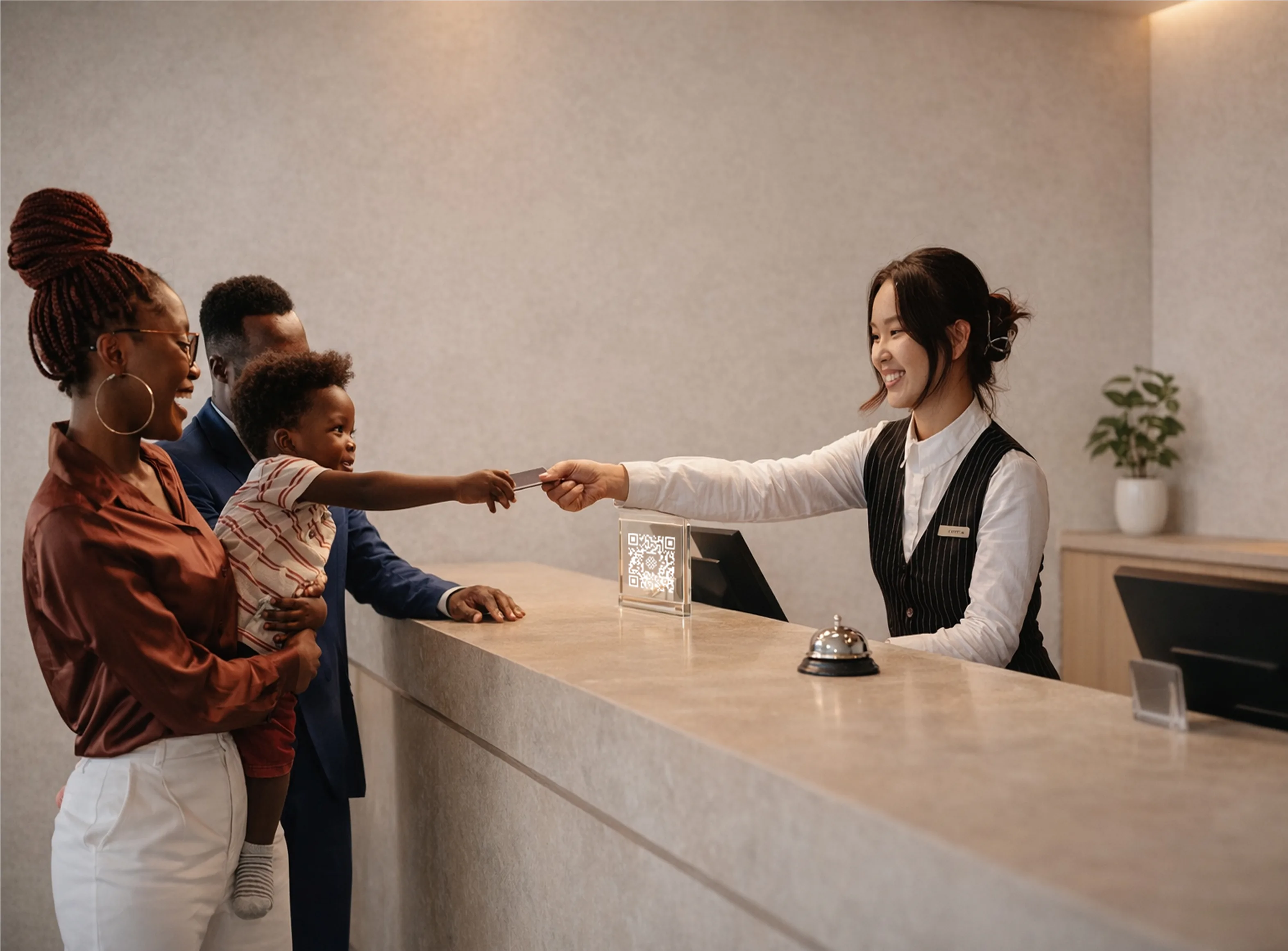 A family checking in at a hotel front desk with a QR code on the counter